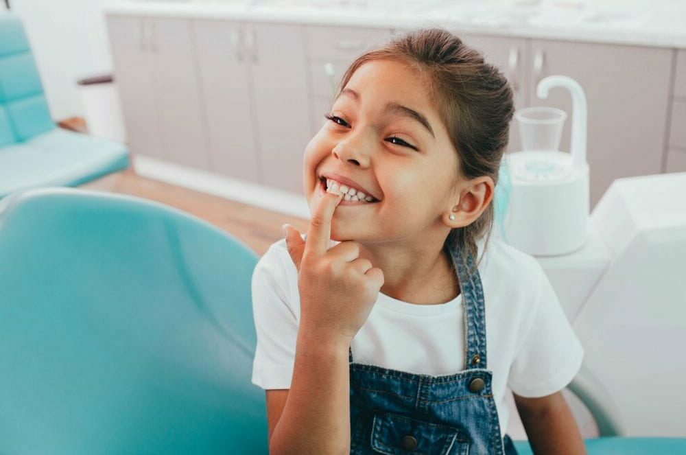 young child pointing at invisalign trays on her teeth